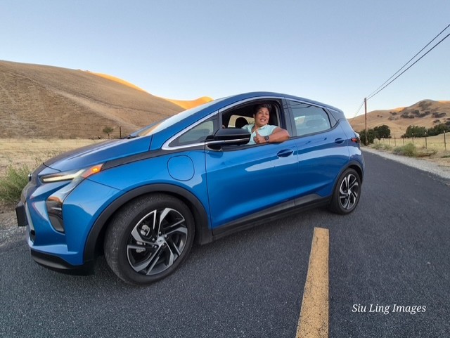 Woman smiling and giving a thumbs up inside a car