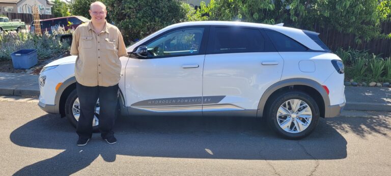 Man smiling next to an electric car